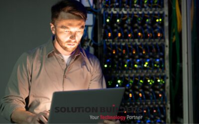 Solution Builders IT professional working on a laptop in a server room